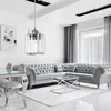 A modern living room with a tufted grey sofa, glass coffee table, and a crystal pendant light. Produktbild-Vorschau