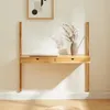 A wooden wall-mounted desk with a laptop and a vase of dried flowers. Voir les images du produit