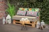 An outdoor seating area with a pallet sofa, cushions, lanterns, and decorative pinecones. Voir les images du produit