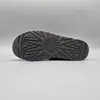 The sole of a black Ugg boot is shown against a light gray background. Voir les images du produit