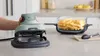 A hand is shown operating a green and gray Ninja CRISPi air fryer, with a glass dish filled with french fries next to it on a kitchen counter. Anteprima dell’immagine prodotto
