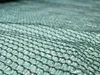 A close-up, abstract view of a dark green shade net, showing the woven texture and hexagonal pattern. Produktbild-Vorschau