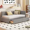A gray upholstered daybed with a pull-out drawer is shown in a bedroom setting. Produktbild-Vorschau