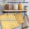 A kitchen scene with jars of food on a shelf and cutting boards hanging from a rack. Produktbild-Vorschau
