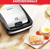 A TEFAL Snack Collection grill and waffle maker is shown on a wooden table, with two toasted sandwiches and a fried egg on plates in the foreground. Voir les images du produit