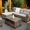 An outdoor lounge set with a coffee table on a patio, surrounded by greenery. Náhľad obrázku produktu