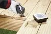 A person is using a power tool to cut a wooden deck, with a deck light installed nearby. Produktbild-Vorschau
