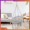 A living room scene with a gray sofa, a wicker chair, and a hanging chair. Voir les images du produit