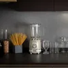 A retro-style blender sits on a dark countertop, with spaghetti and glassware nearby. Produktbild-Vorschau