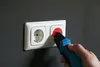 A hand is using a voltage tester to check a wall socket. Náhľad obrázku produktu