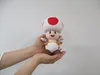 A plush toy of the character Toad from Super Mario is being held in two hands. Anteprima dell’immagine prodotto
