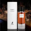 A bottle of Maison Alhambra Smoky EDP perfume and its cylindrical packaging, set against a dark, textured background. Voir les images du produit