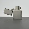 A silver Zippo lighter with its lid open, resting on a dark surface against a white background. Náhľad obrázku produktu