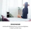 A woman is stretching in bed next to a portable fan. Produktbild-Vorschau