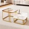 A set of two modern coffee tables with gold metal frames and glass and marble-effect tops, placed on a striped rug in a living room setting. Náhľad obrázku produktu