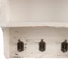 A close-up view of a distressed white wooden shelf with three dark metal hooks. Anteprima dell’immagine prodotto