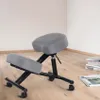 A gray ergonomic kneeling chair with a black metal frame is shown on a wooden floor in a room with white walls. Produktbild-Vorschau