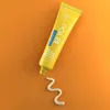 A yellow tube of toothpaste with toothpaste squeezed out in a wavy line on an orange background. Anteprima dell’immagine prodotto