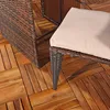 A close-up view of outdoor furniture, specifically a wicker ottoman with a beige cushion, placed on a wooden deck. Anteprima dell’immagine prodotto