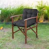 A black cushion on a wooden chair in a garden setting. Produktbild-Vorschau