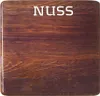 A close-up of a wooden surface with the word 'NUSS' printed on it. Produktbild-Vorschau