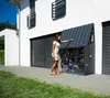 A woman is opening a bicycle storage unit attached to a modern house. Náhľad obrázku produktu