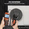 A person is holding an anemometer and a display unit next to an outdoor air conditioning unit in the rain. Voir les images du produit
