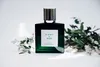 A perfume bottle is displayed on a white surface with sprigs of white flowers and green leaves. Podgląd zdjęcia produktu
