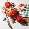 A collection of red bell peppers, garlic, red onion, and a jar of pickled peppers arranged on wooden cutting boards with a green checkered cloth. Podgląd zdjęcia produktu