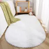 A fluffy white rug is placed on a wooden floor next to a bed with a green blanket. A small stuffed dinosaur toy sits on a shelf in the background. Anteprima dell’immagine prodotto