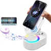 A hand holding a smartphone over a white speaker stand with colorful lights and musical notes emanating from it. Produktbild-Vorschau