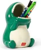 A green ceramic dinosaur pen holder with pens inside, on a white background. Produktbild-Vorschau