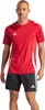A man wearing a red Adidas t-shirt and black Adidas shorts, standing against a white background. Anteprima dell’immagine prodotto