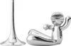A silver bottle opener shaped like a person lying down, next to a silver stand. Náhľad obrázku produktu