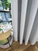 A close-up view of a light gray curtain with folds, next to a small round wooden table with a book and a cup. Produktbild-Vorschau