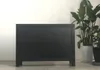 A black sideboard is shown against a white wall with plants in pots to the right. Produktbild-Vorschau