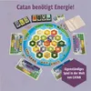 A board game with hexagonal tiles representing land and sea, surrounded by game pieces, cards, and a drawstring bag. Produktbild-Vorschau