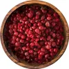 A close-up, top-down view of pink peppercorns in a wooden bowl. Produktbild-Vorschau