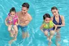 Two children wearing swim vests are being held by adults in a swimming pool. Náhled obrázku produktu