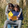 Two young people are sitting outdoors, looking at a notebook. Podgląd zdjęcia produktu