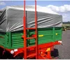 A close-up view of a green and red agricultural trailer covered with a gray tarp. Produktbild-Vorschau