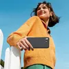 A young woman holding a black smartphone case outdoors. Produktbild-Vorschau