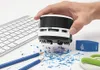 A hand holding a mini desk vacuum cleaner over a desk with a keyboard, pencils, and pencil shavings. Anteprima dell’immagine prodotto