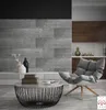 A modern living room with a grey textured wall, a comfortable armchair, and a coffee table. Produktbild-Vorschau