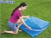 A woman is kneeling on grass, folding a blue solar cover. Náhled obrázku produktu