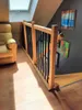 A wooden railing with black balusters on a staircase, with a yellow armchair and artwork on the wall. Produktbild-Vorschau