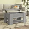 A lift-top coffee table is shown in a living room setting, placed on a rug in front of a sofa. A bowl of fruit sits on the table. Produktbild-Vorschau