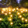 Solar garden lights illuminating a garden at dusk with houses in the background. Produktbild-Vorschau