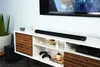 A soundbar and subwoofer are set up in a living room entertainment center. Produktbild-Vorschau