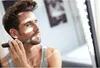 A man is trimming his beard in front of a mirror. Podgląd zdjęcia produktu